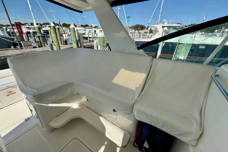 Slide: The Image of 2003 Tiara Yachts 3500 Open interior seating with white cushions at a marina. - 18