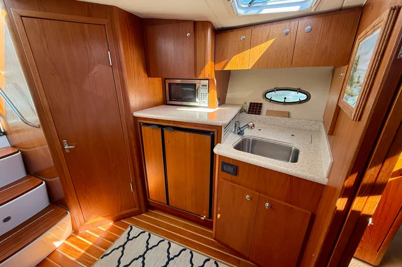 Slide: The Image of Interior of 2003 Tiara Yachts 3500 Open, featuring a compact kitchen with wood cabinetry. - 25