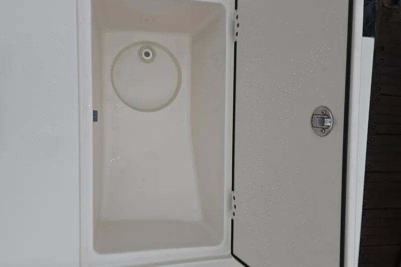 Slide: The Image of 2021 Carolina Skiff 19 LS storage compartment with open hatch and latch. Molded in 5-gallon bucket storage - 19