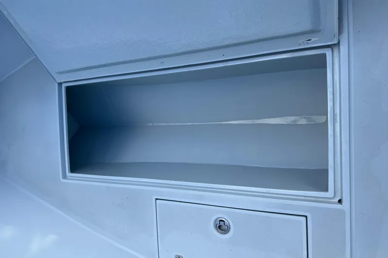 Slide: The Image of 2004 SeaVee Center Console storage compartment with secure latch, open and empty. - 25
