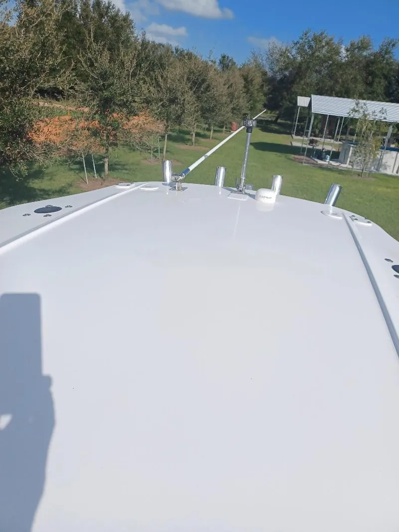 Slide: The Image of 2022 Everglades 243 Center Console boat on grassy area with trees and blue sky. - 12