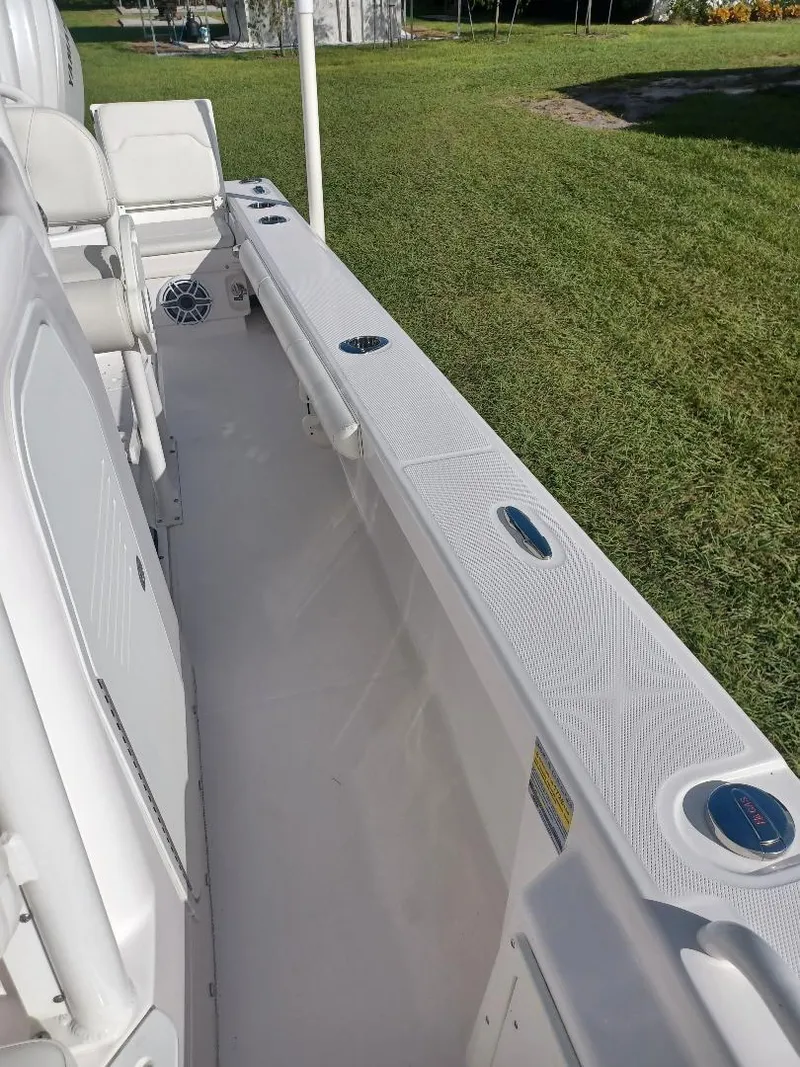 Slide: The Image of 2022 Everglades 243 Center Console boat, white interior, docked on grassy area. - 16