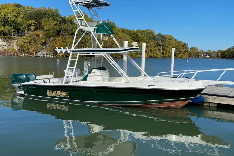 The Image of Green and white Salt Shaker 30 boat named "Marie" docked on a calm lake. - 0