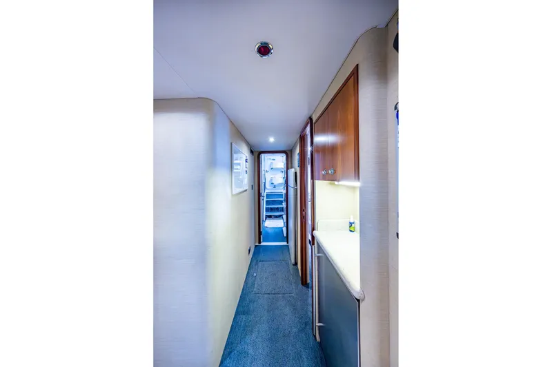 Slide: The Image of Narrow hallway inside 2006 Westport 112 yacht, featuring wood cabinets and carpeted floor. - 111