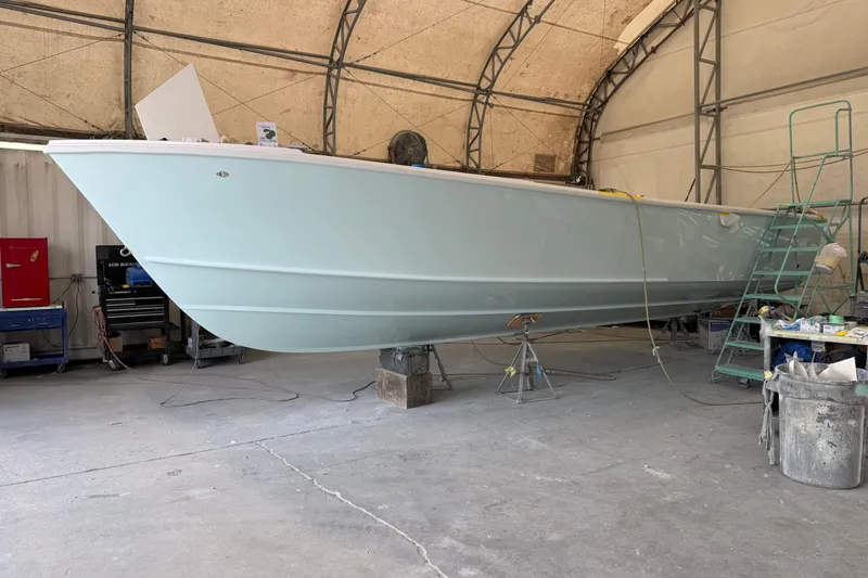 Slide: The Image of 2026 Albury Brothers 27 boat cruising near rocky shoreline with palm trees. - 2