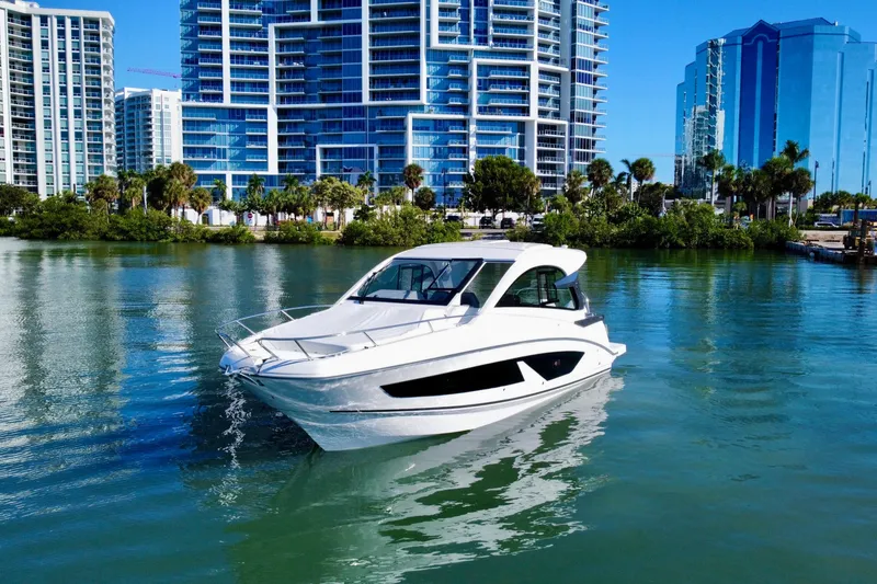 Slide: The Image of 2026 Beneteau Flyer 10 cruising in urban waterfront, modern buildings in background. - 2