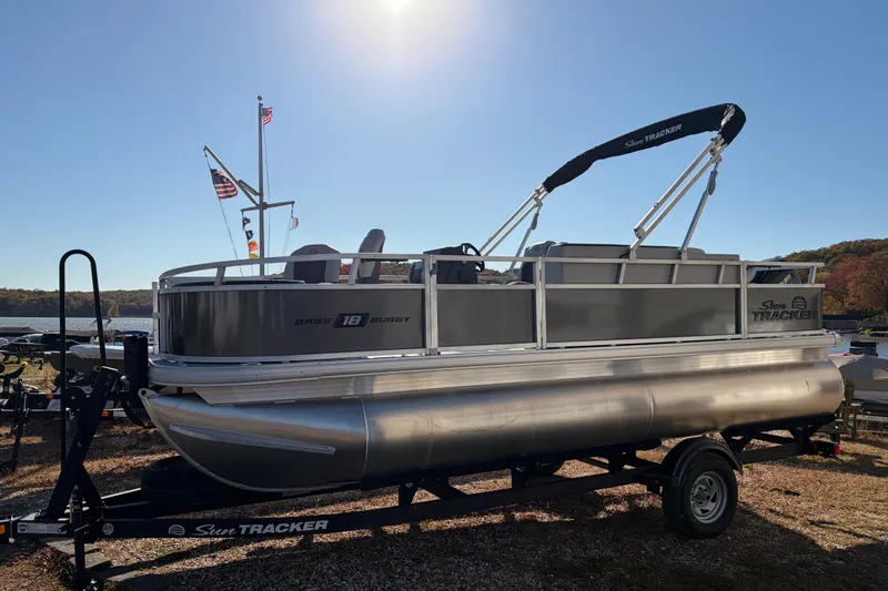 Slide: The Image of 2026 Sun Tracker Bass Buggy 18 DLX pontoon boat on trailer by a lake. - 12