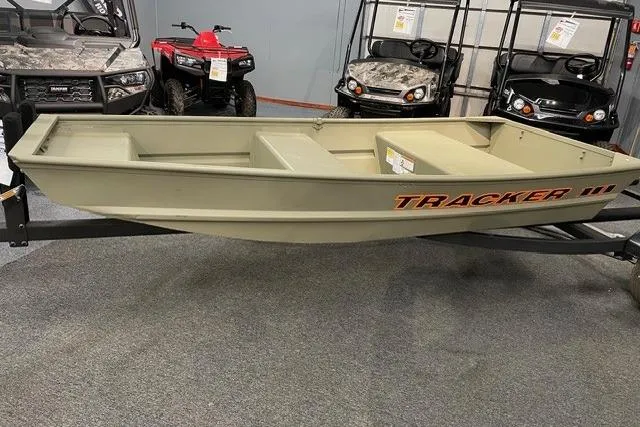The Image of 2026 Tracker Grizzly 10 Jon boat displayed indoors with off-road vehicles. - 0