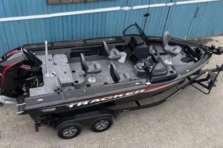 Slide: The Image of 2026 Tracker Targa V-19 Combo boat with seating, motor, and trailer, parked by a blue wall. - 6