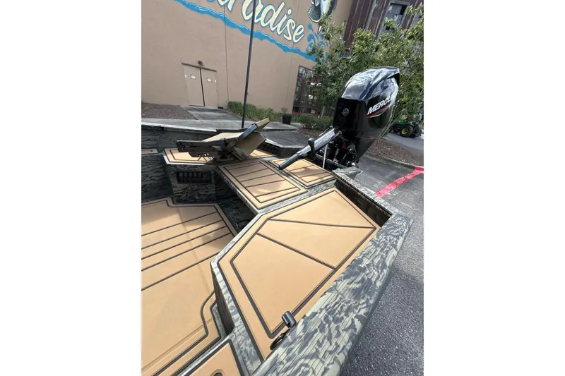 Slide: The Image of 2026 Tracker Grizzly 1650 T Prairie Wings Edition boat with Mercury engine, parked outdoors. - 6