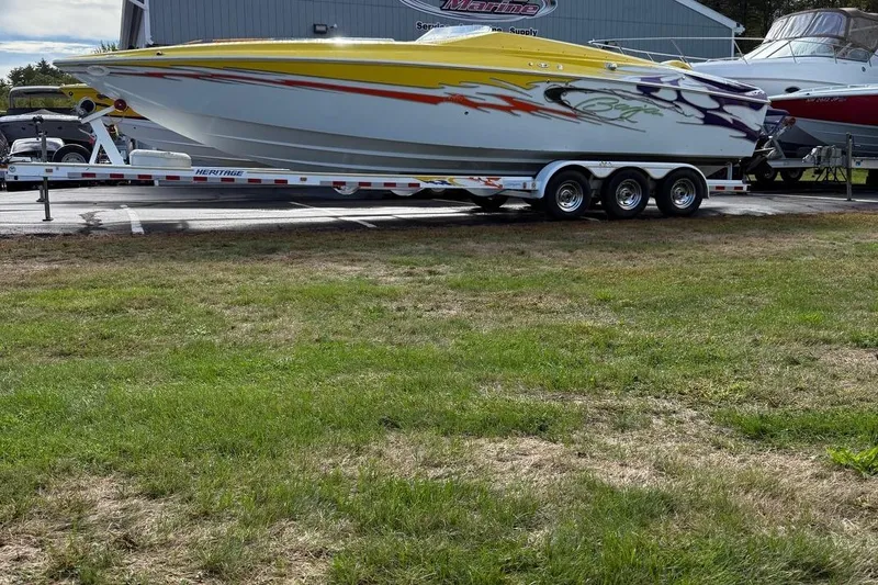 The Image of 2005 Baja 30 Outlaw speedboat with vibrant graphics on a trailer, parked outdoors. - 0