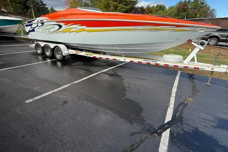 Slide: The Image of 2005 Baja 30 Outlaw speedboat on trailer, vibrant graphics, parked outdoors. - 2