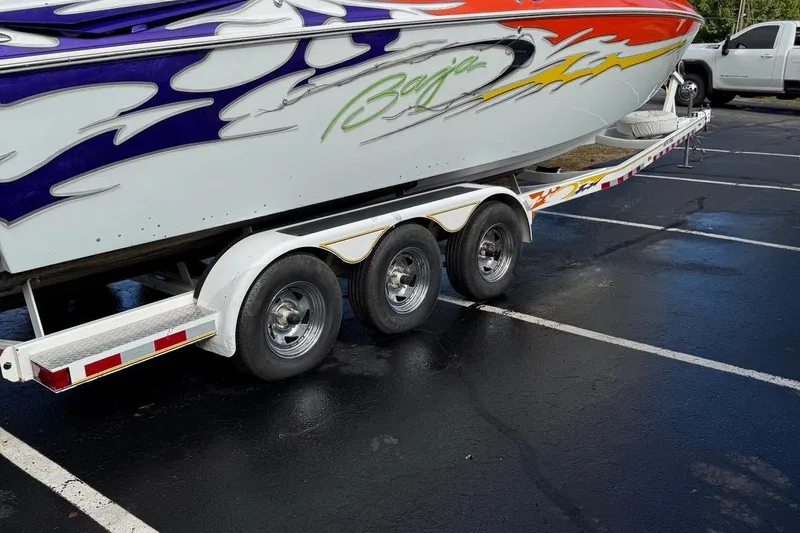 Slide: The Image of 2005 Baja 30 Outlaw boat on trailer with colorful graphics in parking lot. - 4