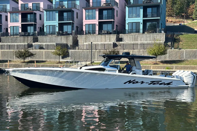The Image of 2025 Nor-Tech 450 Sport Center Console boat docked near colorful waterfront buildings. - 1