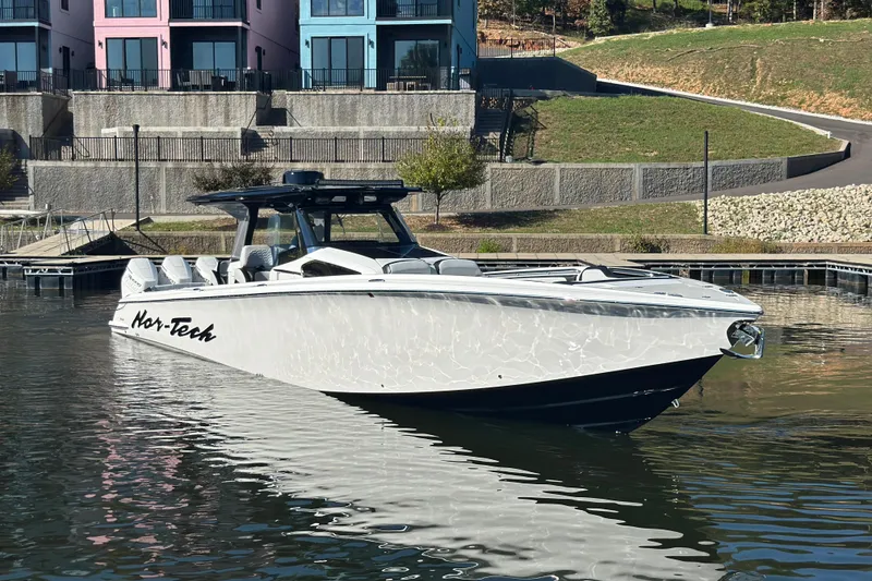 Slide: The Image of 2025 Nor-Tech 450 Sport Center Console boat docked near colorful buildings. - 12