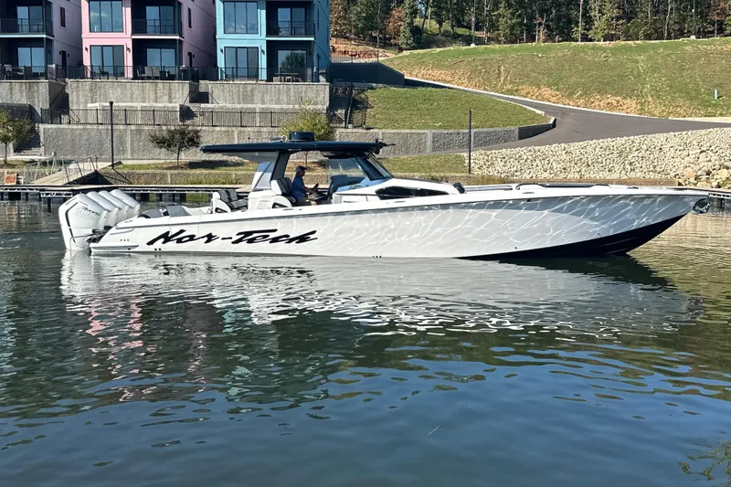 Slide: The Image of 2025 Nor-Tech 450 Sport Center Console boat on calm water near modern buildings. - 15