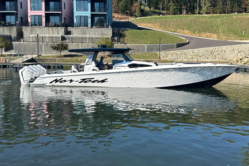 Slide: The Image of 2025 Nor-Tech 450 Sport Center Console boat on calm water near colorful buildings. - 16