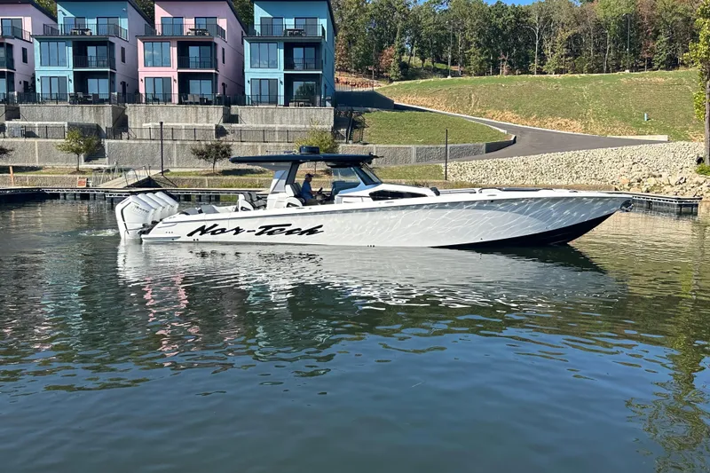 Slide: The Image of 2025 Nor-Tech 450 Sport Center Console boat on calm water near colorful buildings. - 17