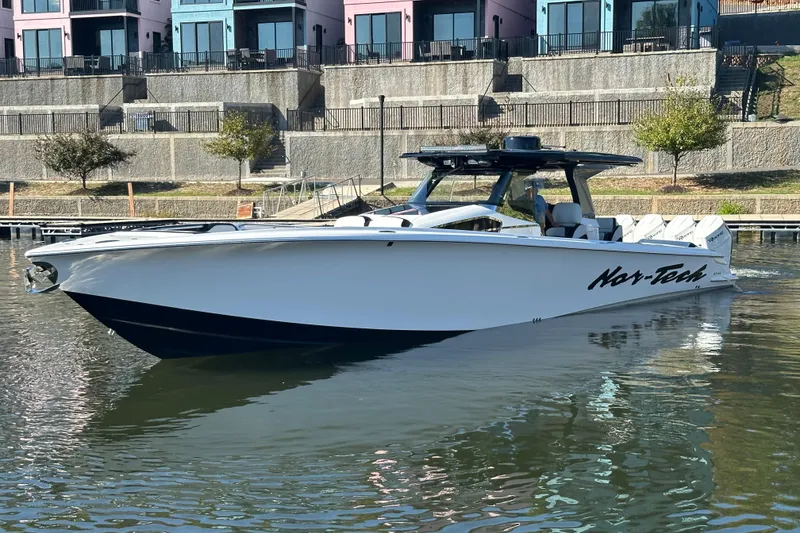 Slide: The Image of 2025 Nor-Tech 450 Sport Center Console boat on calm water near colorful buildings. - 5