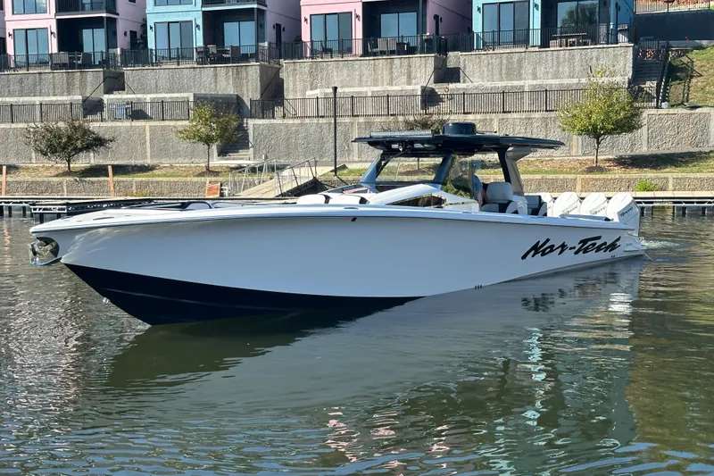 Slide: The Image of 2025 Nor-Tech 450 Sport Center Console boat docked near colorful buildings. - 6