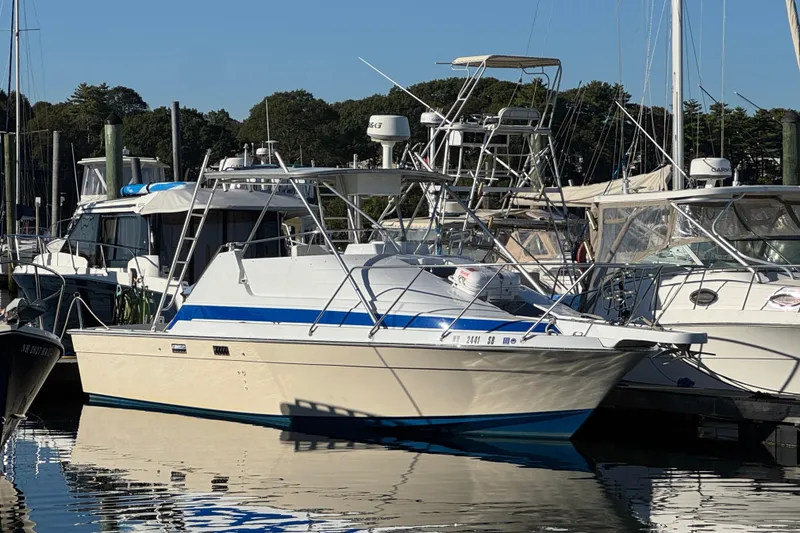 The Image of 1986 Luhrs Tournament 290 boat docked at marina, surrounded by other vessels. - 0