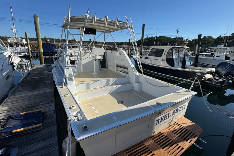 Slide: The Image of 1986 Luhrs Tournament 290 boat docked at marina, featuring open deck and canopy. - 10