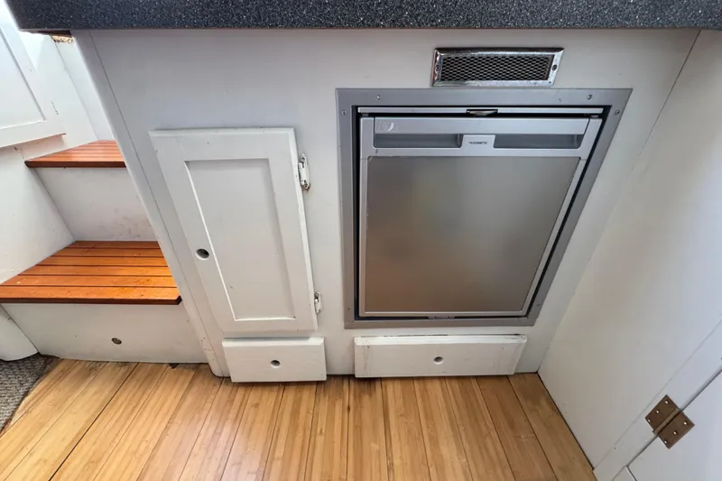 Slide: The Image of 1986 Luhrs Tournament 290 interior with compact fridge and wooden steps. - 25