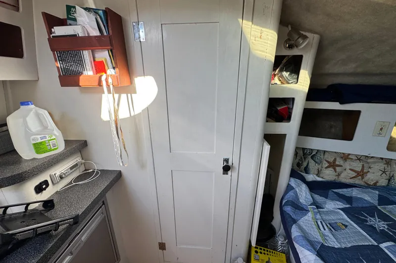 Slide: The Image of 1986 Luhrs Tournament 290 cabin interior with bed, storage, and countertop. - 26