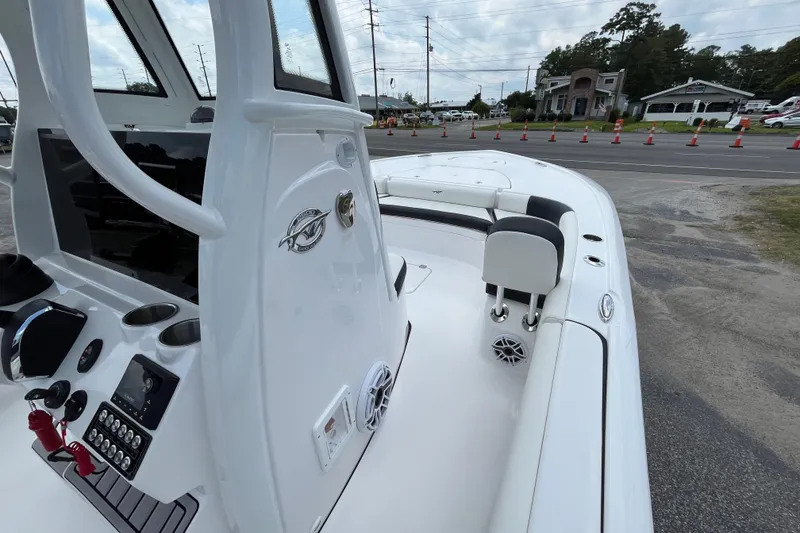 Slide: The Image of 2023 Tidewater 2500 Carolina Bay boat interior with control panel and seating, parked near road. - 10