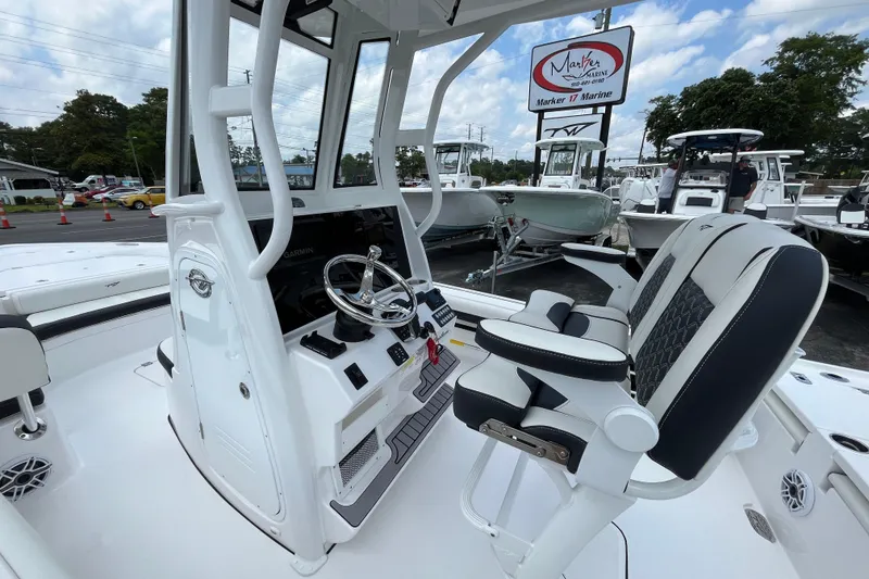 Slide: The Image of 2023 Tidewater 2500 Carolina Bay boat interior with helm and seating at a marine dealership. - 15