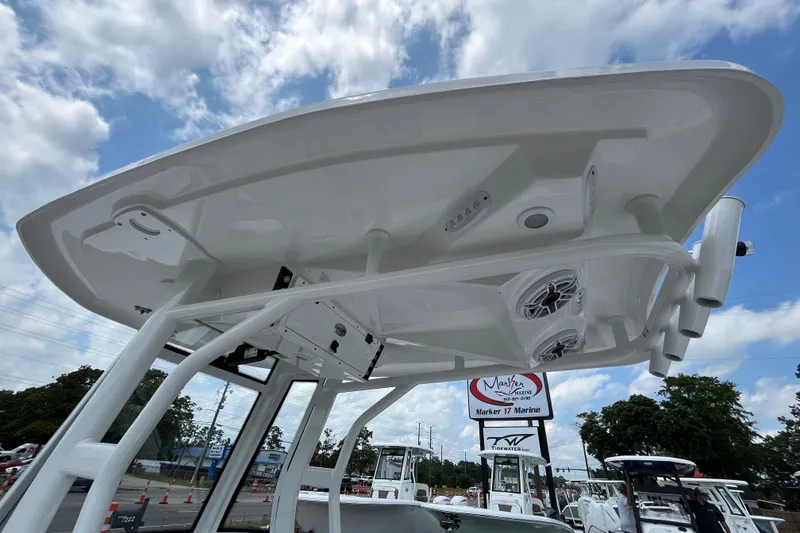 Slide: The Image of 2023 Tidewater 2500 Carolina Bay boat with T-top and speakers, under a partly cloudy sky. - 16