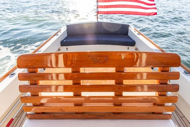 Slide: The Image of 2002 Hinckley Talaria 29C boat with wooden seating and American flag on water. - 13