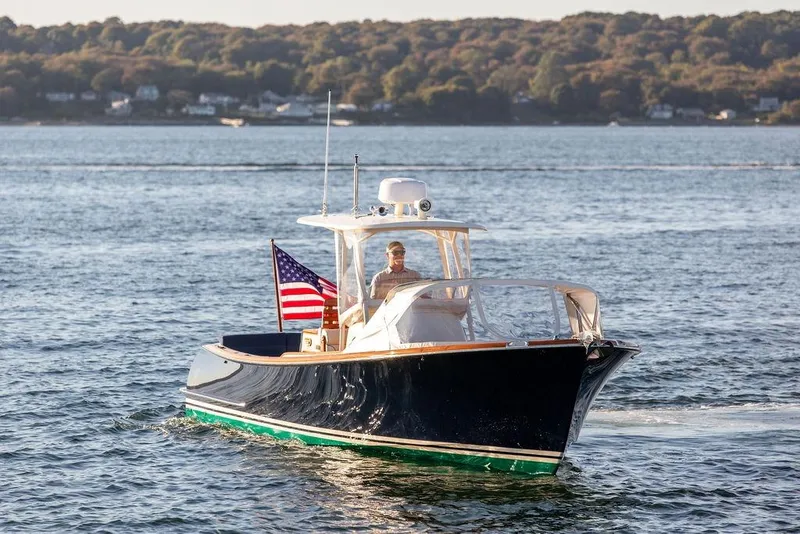 Slide: The Image of 2002 Hinckley Talaria 29C cruising on a scenic lake with American flag. - 8