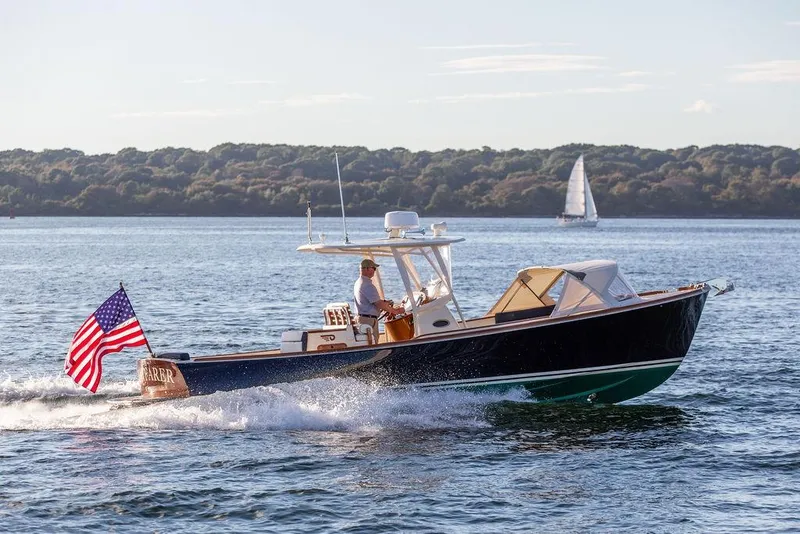 The Image of 2002 Hinckley Talaria 29C cruising on water with American flag, scenic background. - 0