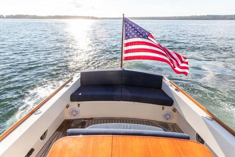 Slide: The Image of 2002 Hinckley Talaria 29C boat with American flag on open water. - 12