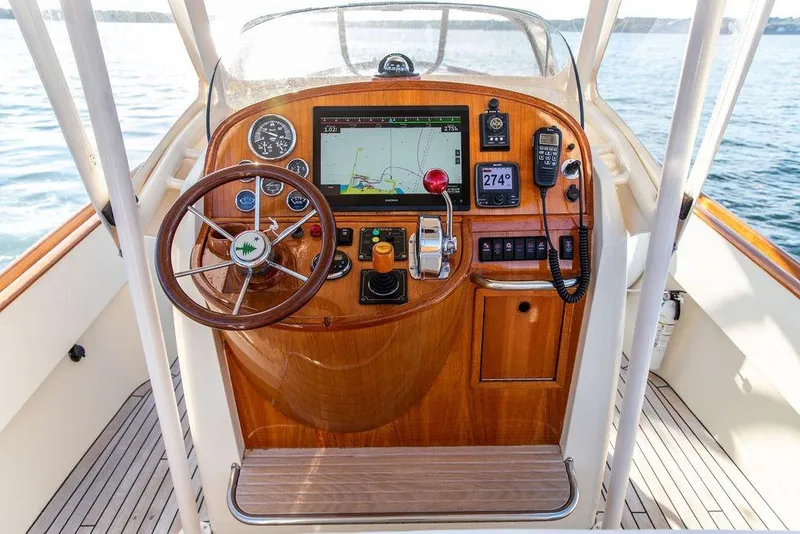 Slide: The Image of Hinckley Talaria 29C 2002 boat dashboard with navigation equipment and wooden steering wheel. - 22