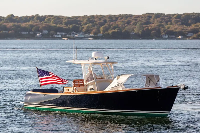 Slide: The Image of 2002 Hinckley Talaria 29C boat on water with American flag, scenic background. - 4