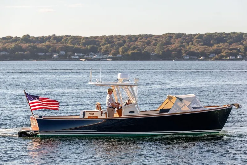 Slide: The Image of 2002 Hinckley Talaria 29C cruising on a serene lake with American flag. - 5