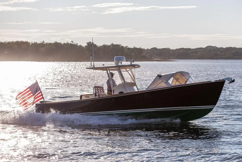 Slide: The Image of 2002 Hinckley Talaria 29C cruising on a sunlit lake with American flag. - 6