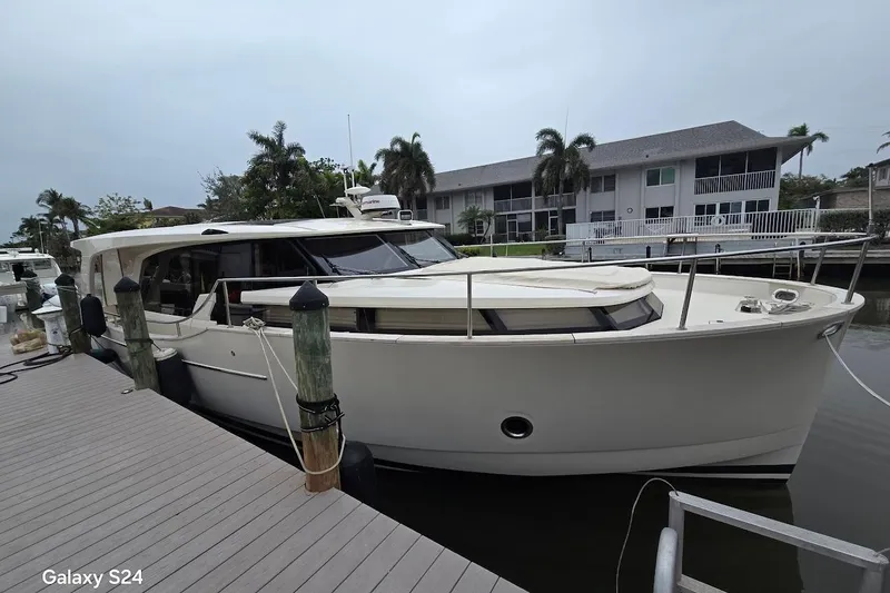 Slide: The Image of 2019 Greenline 40 yacht docked at marina, surrounded by palm trees and waterfront homes. - 20