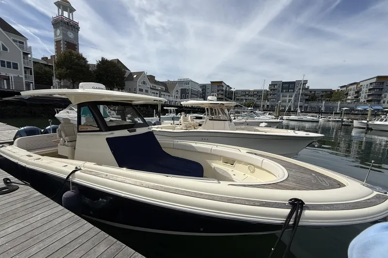 Slide: The Image of 2019 Chris-Craft Catalina 30 docked at a marina with waterfront buildings in the background. - 2