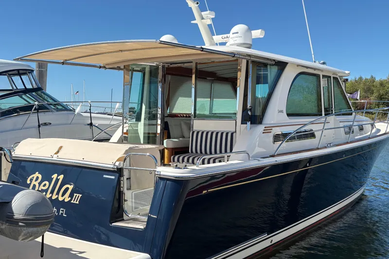 The Image of 2023 Sabre 45 Salon Express yacht docked by a pier, featuring sleek design and American flags. - 0