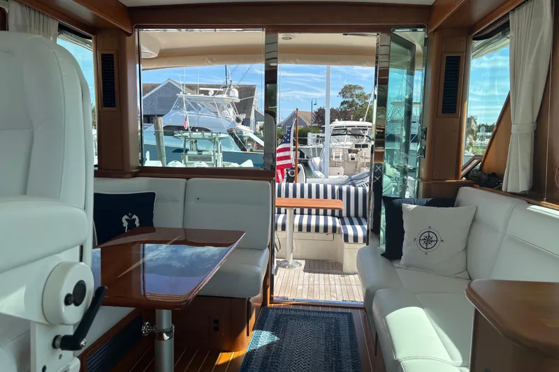 Slide: The Image of 2023 Sabre 45 Salon Express yacht with striped seating and wooden table at marina. - 4