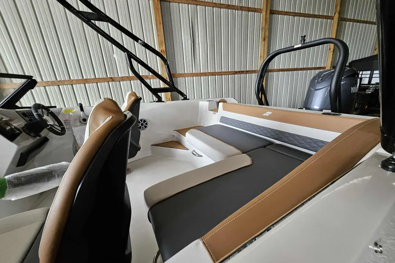 Slide: The Image of 2025 Starcraft SVX 210 OB boat interior with brown and black seating in a storage facility. - 6