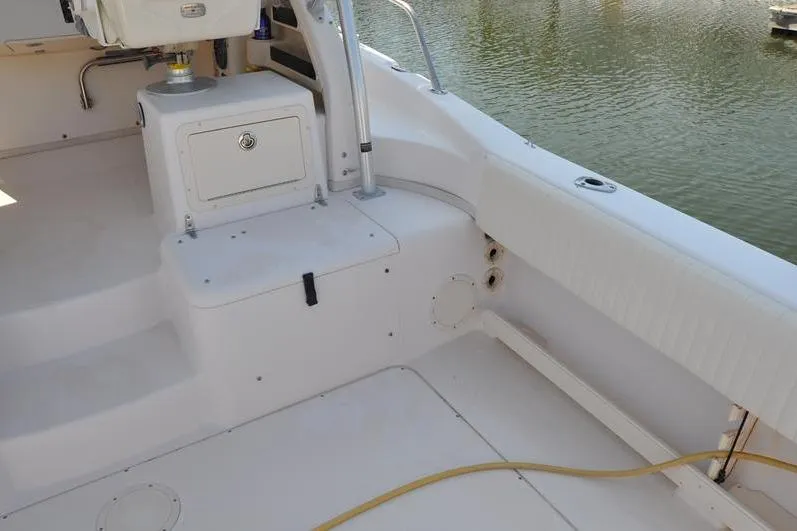 Slide: The Image of 2010 Grady-White Chesapeake 290 boat interior with seating and storage, docked by water. - 17