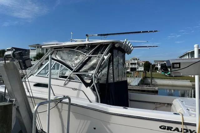 Slide: The Image of 2010 Grady-White Chesapeake 290 boat docked, featuring fishing rods and clear skies. - 3