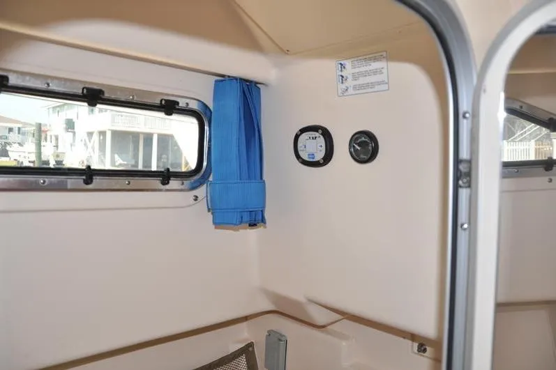 Slide: The Image of Interior view of 2010 Grady-White Chesapeake 290 boat cabin with window and blue curtain. - 36