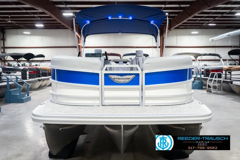 Slide: The Image of 2026 Bennington 24 MOFB pontoon boat in showroom, featuring blue and white design. - 5