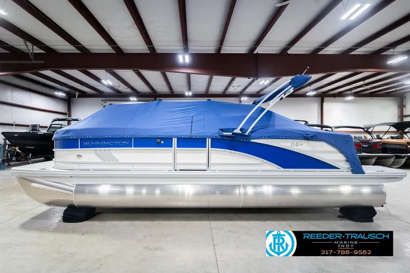 Slide: The Image of 2026 Bennington 24 MOFB pontoon boat with blue cover in indoor showroom. - 65