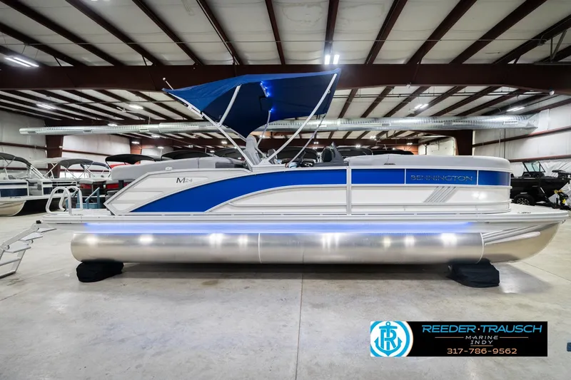 Slide: The Image of 2026 Bennington 24 MOFB pontoon boat with blue accents in a showroom. - 7